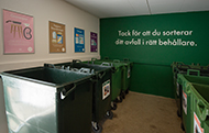 Den ommålade miljöstugan med FB-grön fondvägg och texten Tack för att du sorterar ditt avfall i rätt behållare. Nya sorteringsskyltar på väggen.