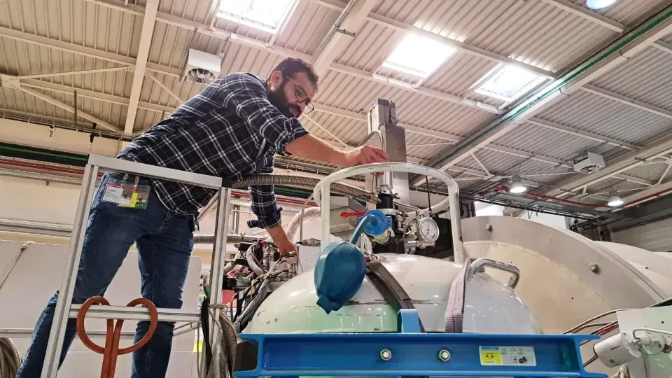 Photo of a man working on a big scientific instrument.