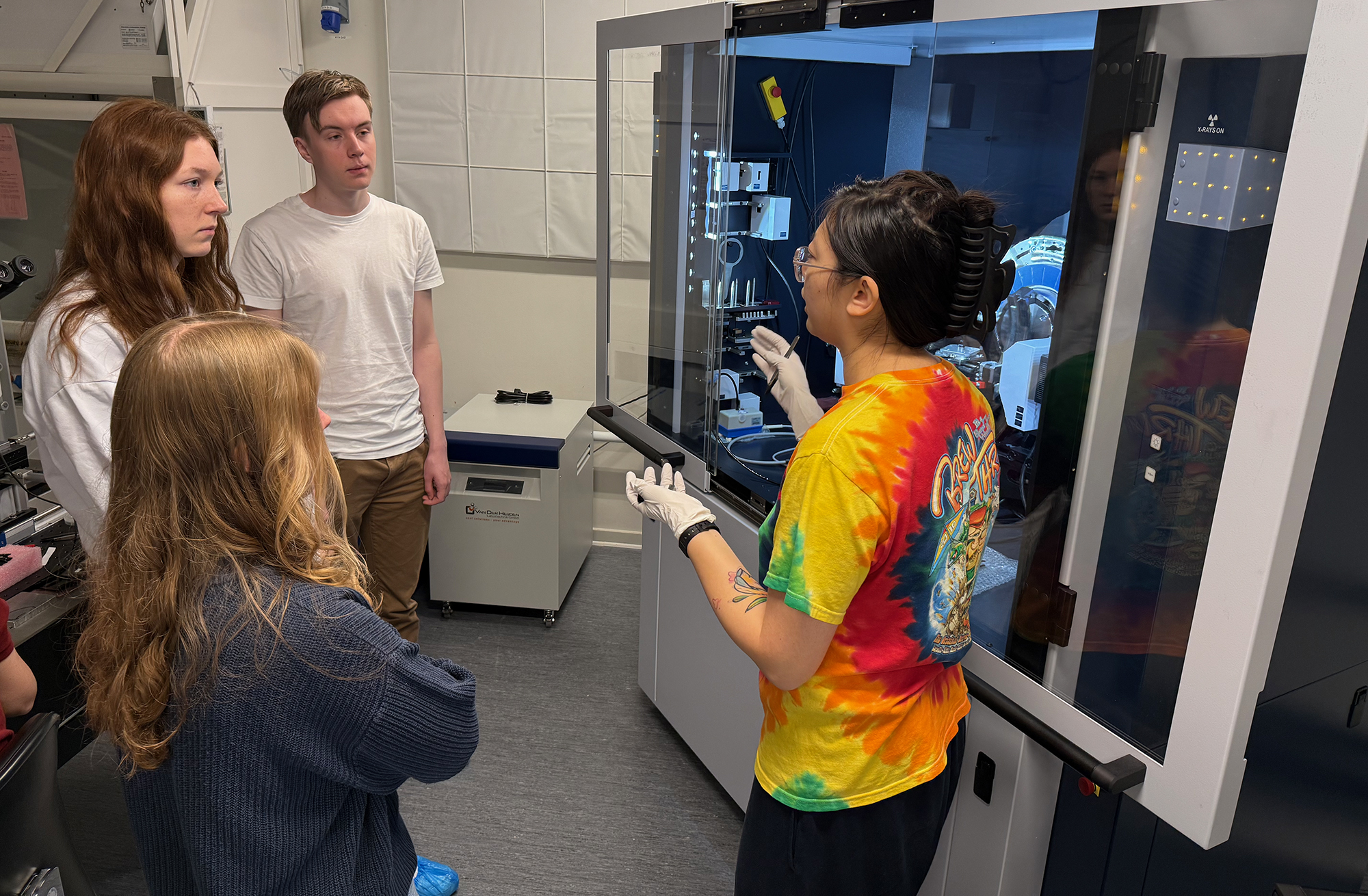 Photo of four people talking in front of a scientific machine.