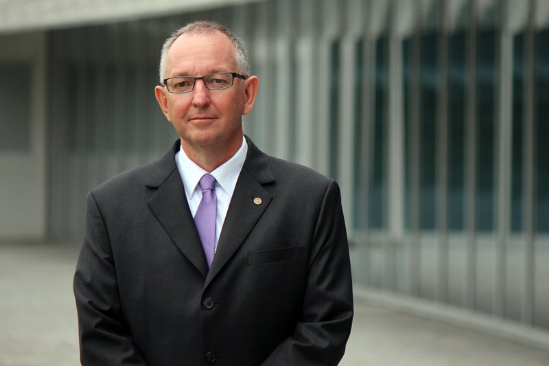 Photo of a man in suit and purple tie.