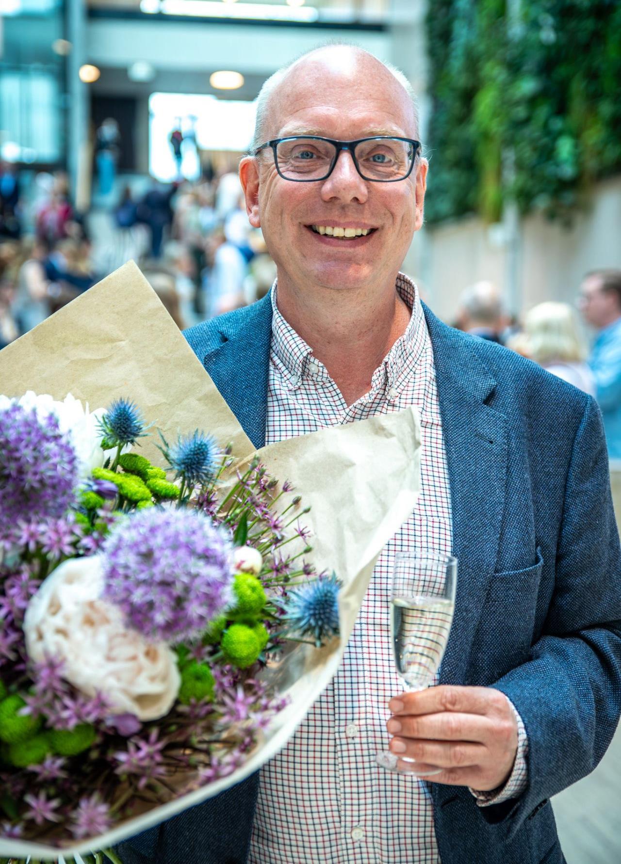 A man holding flowers and a wine glass. Photo.