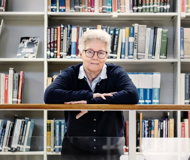 A woman in front of book shelves. Photo.