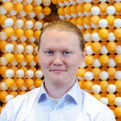 A man in front of orange and white table tennis balls. Photo.