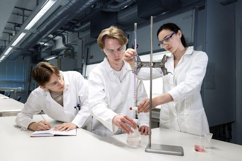 Three people in white coats conducting a scientific experiment. Photo.