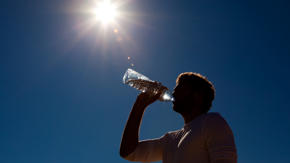 Man dricker vatten under sol. Foto: MostPhotos.