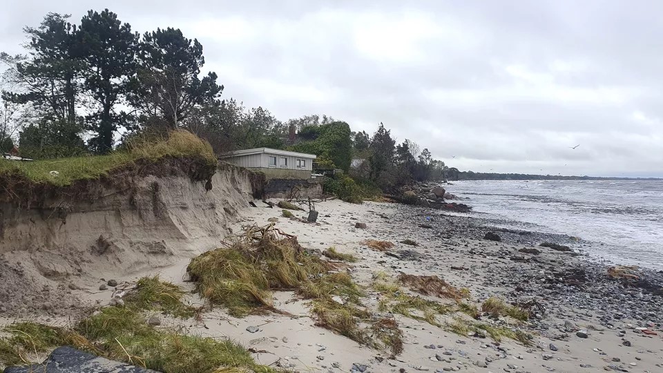 Eroderad strand med hus med bortspolad grund. Foto: Caroline Hallin.