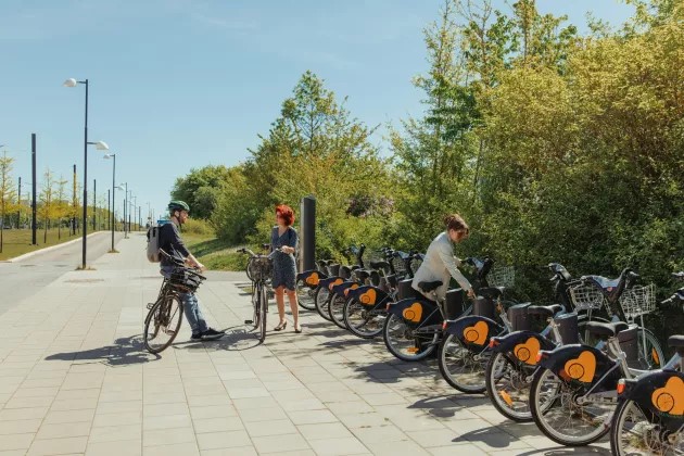 Personer vid cykel och cykelställ i en stadsmiljö.