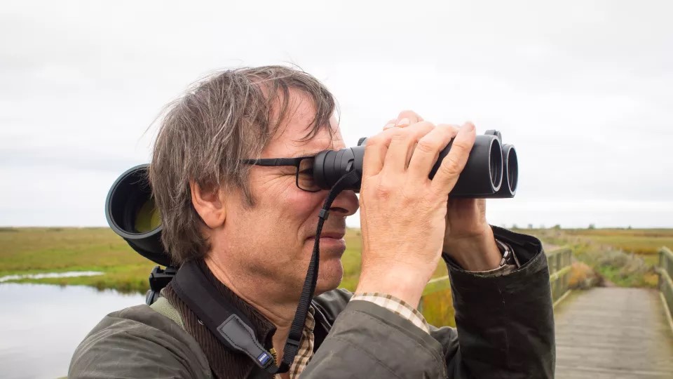 Henrik Smith tittar i en kikare. Foto.