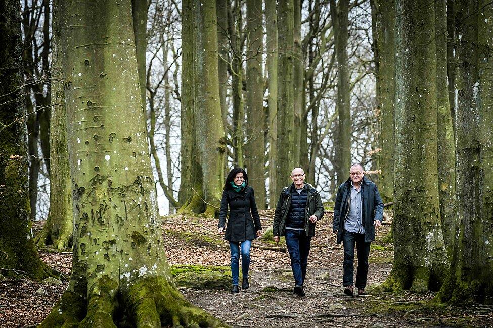 Tre personer går i en skog. Foto: Kenneth Ruona.