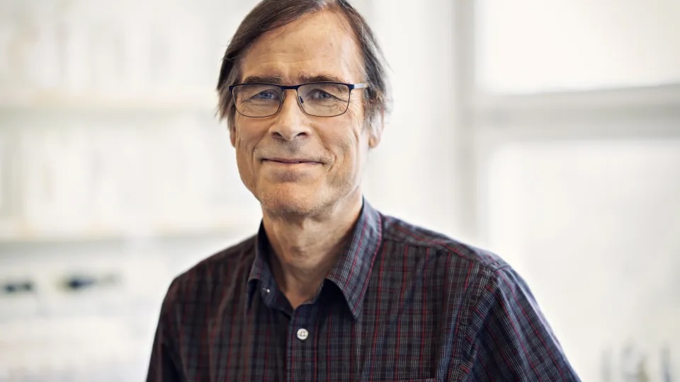Porträtt av Henrik Smith som tittar in i kameran och ler. Foto.