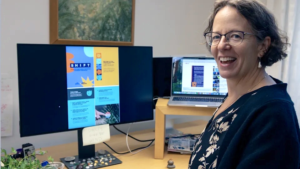 Forskaren Kimberly Nicholas står framför en datorskärm och tittar leende bak mot kameran. Foto.