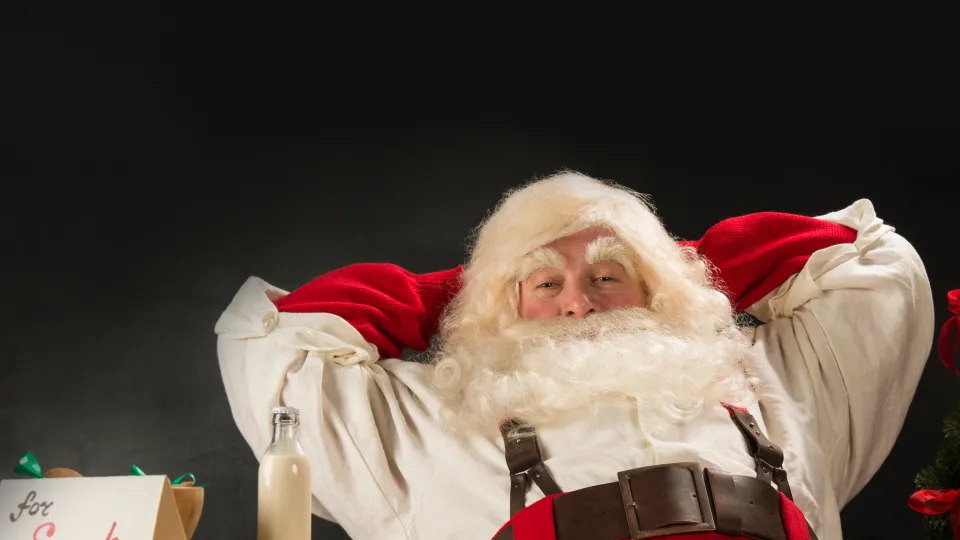 Jultomten sitter tillbakalutad med händerna bakom nacken. Foto.