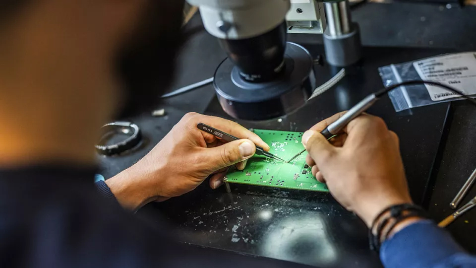 Photo of hands putting electronic devices together.