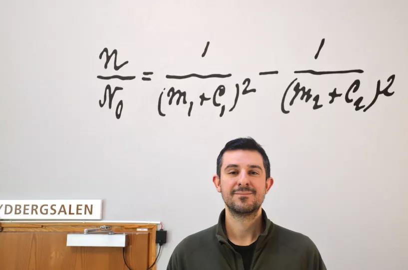 Photo of a man standing under the Rydberg formula.