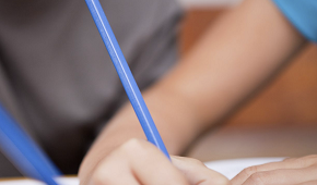 Ett barns hand håller i en penna och skriver.