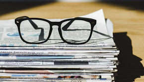 Ett par glasögon på en hög med tidningar på ett bord.