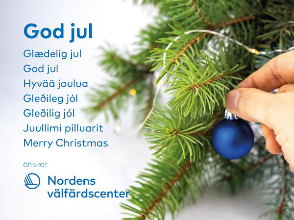 Texten god jul på åtta olika språk och hand som dekorerar en grankvist med en blå julgranskula.