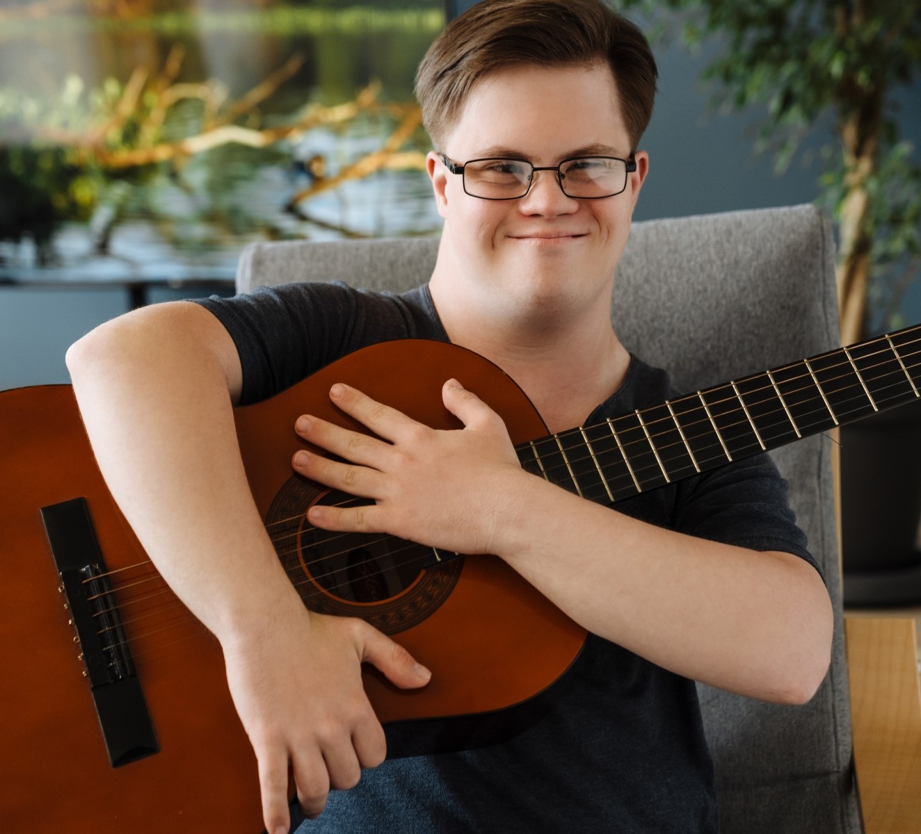 Ung man med Downs syndrom sitter med en gitarr i famnen