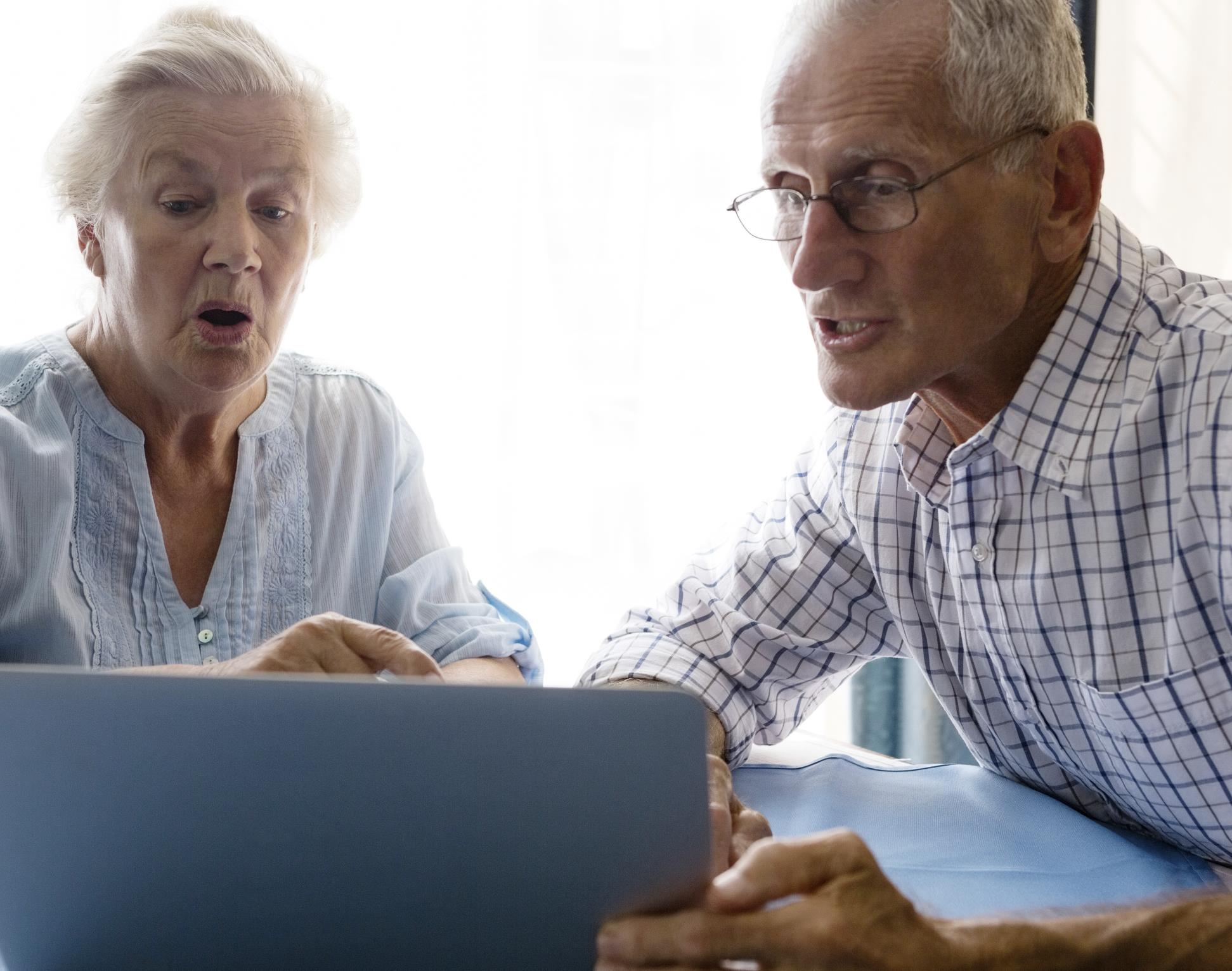 Äldre man och kvinna sitter vid en datorskärm