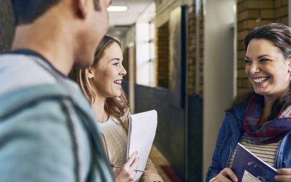 Smiling teacher with two happy students in corridor