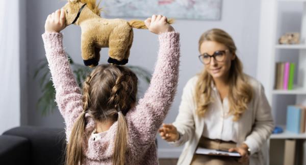 Young girl holding a toy and talking to a woman