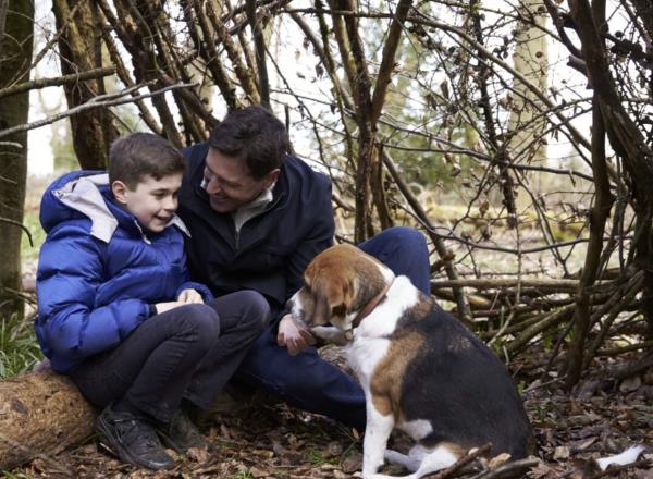 Young boy and dad outside with a sitting dog