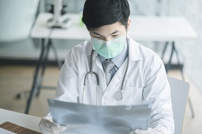 Manlig läkare med munskydd tittar på röntgenbild
