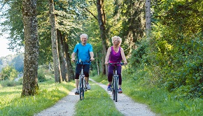 Äldre man och kvinna ute och cyklar en solig sommardag
