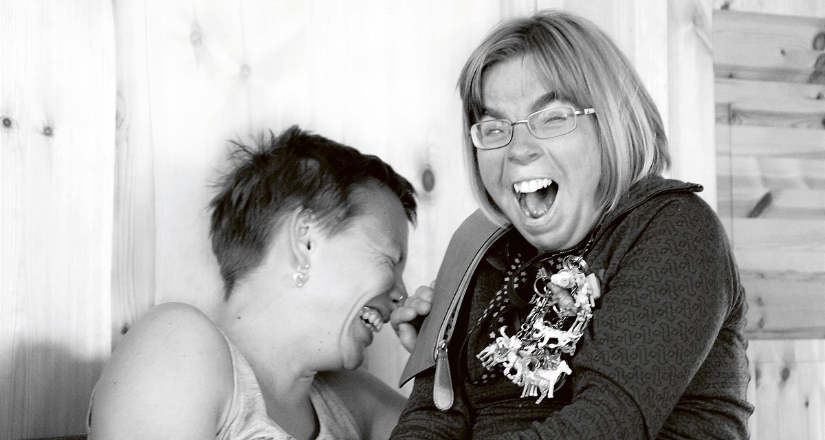 Svartvitt porträtt av två kvinnor som skrattar stort ihop