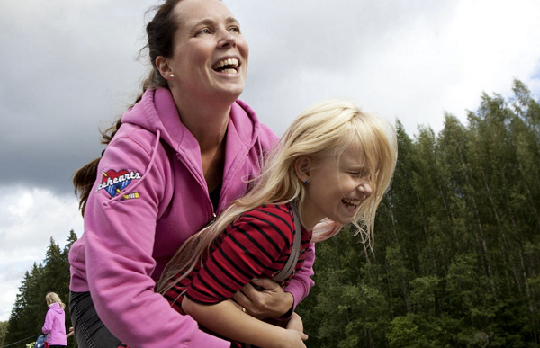 Glad kvinna kramar om skrattande barn.