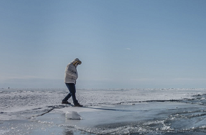 A person walking on ice in sunny weather.