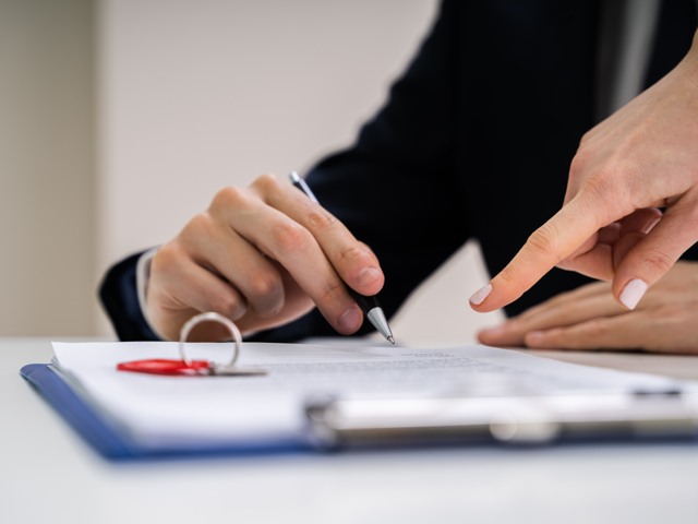 Två personers händer vid kontraktskrivning på papper (bild)