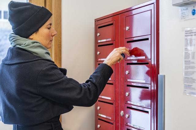 Bild: Kvinna tar ut post från bostbox