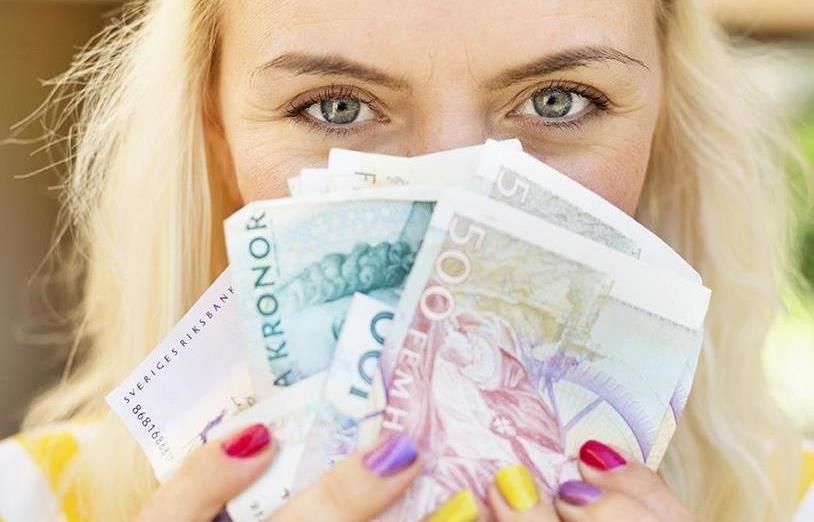 Bild: Kvinna håller pengar framför ansiktet