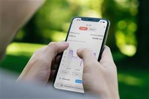 Två händer håller i en mobil där man ser diagram på skärmen.