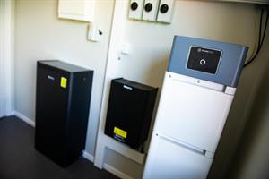 Två batterienheter sitter i vinkel på två källarväggar.