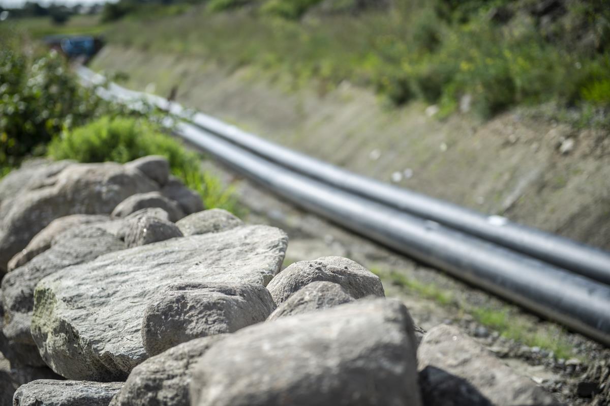 Stenmur och i en suddig bakgrund ett par exponerade fjärrvärmerör.