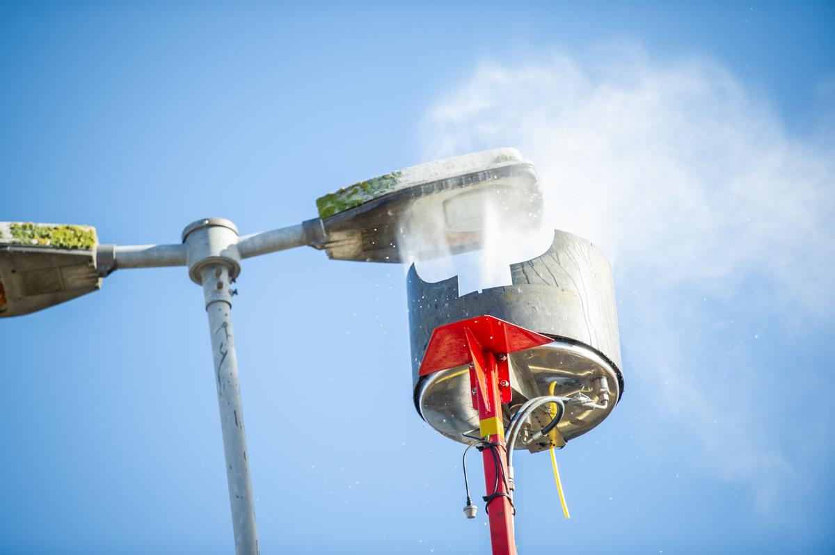 En tvätt som sprutar vatten underifrån på en gatubelysning.