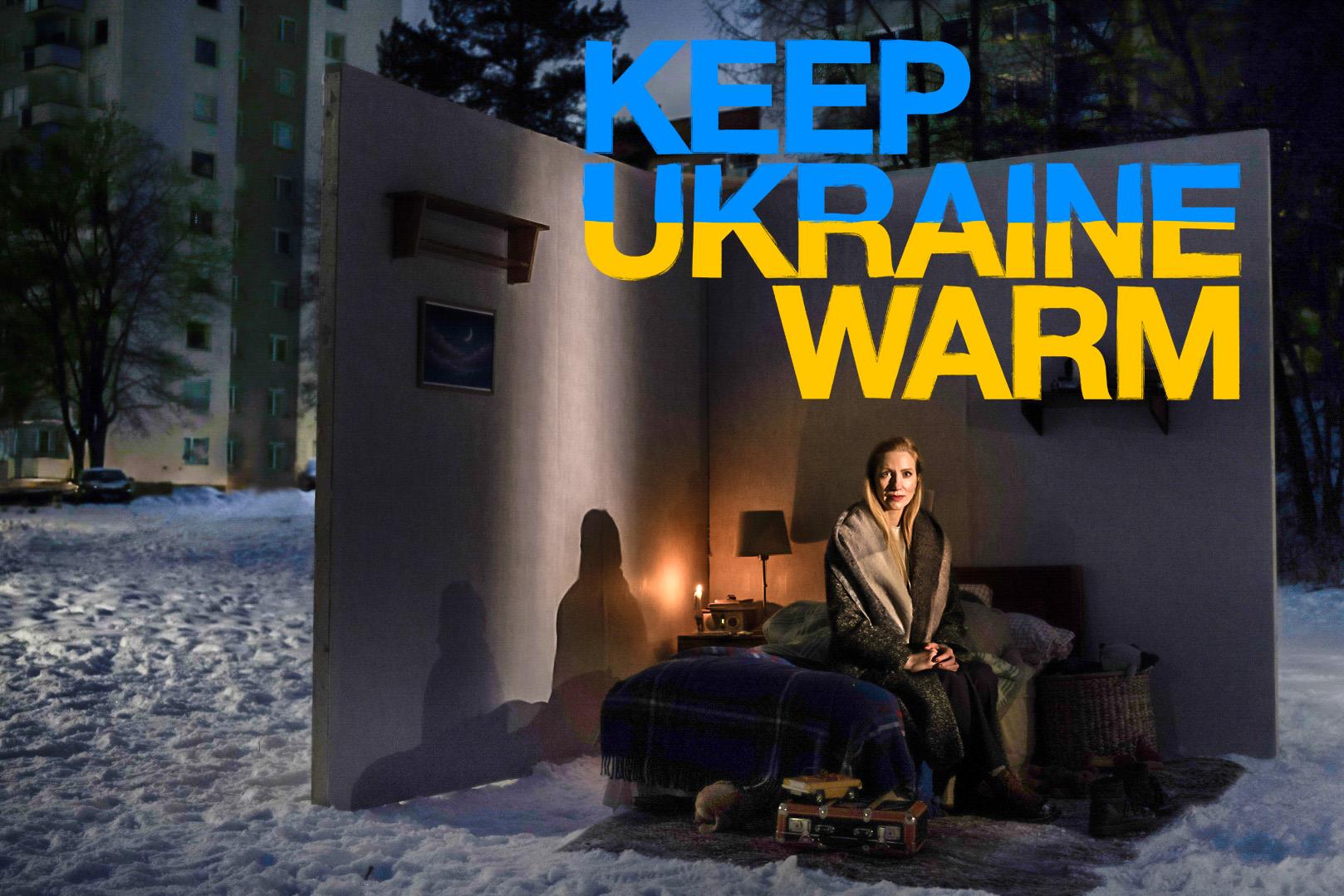 En kvinna sitter utomhus på en gårdsplan med höga hus runtom, på säng med lampa och två väggar.