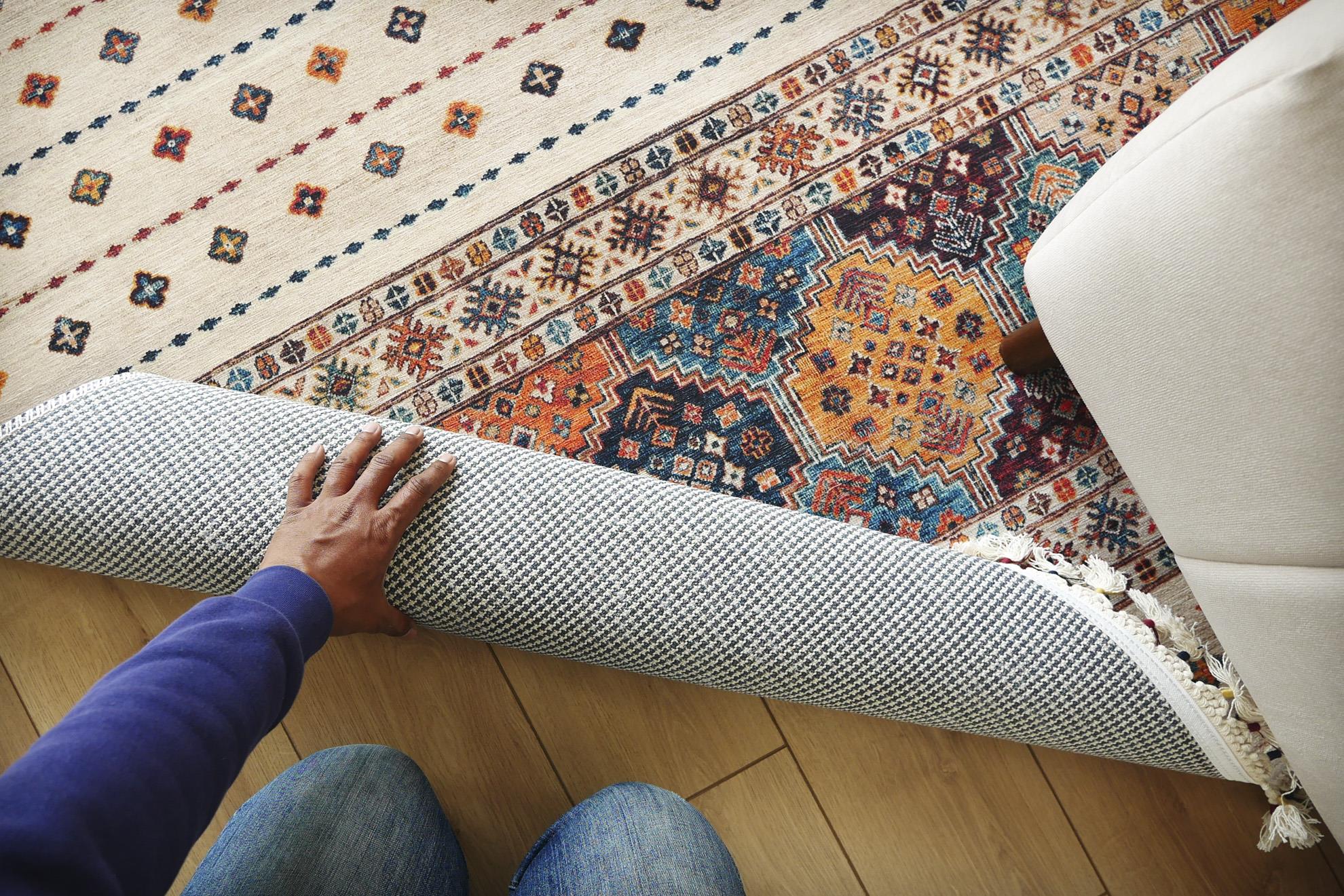 Flerfärgad matta bredvid vit soffa som rullas ihop.