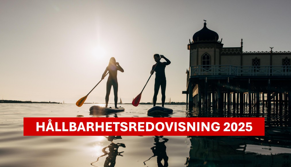 Glad man står framför ett vitt hus med solpaneler.