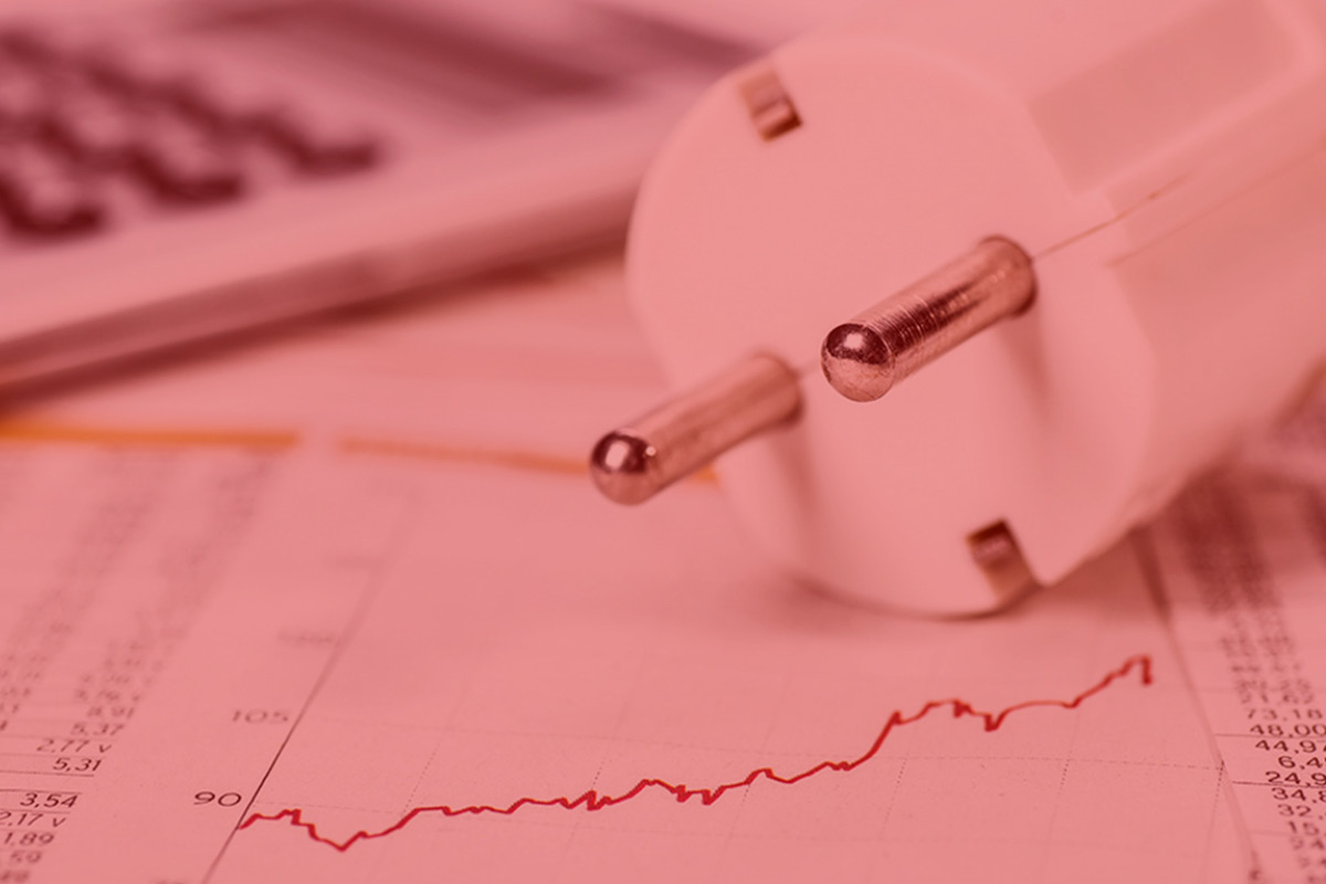 Närbild på en stickkontakt liggandes på et papper med diagramkurva. Bilden har en rödrosa ton över sig.