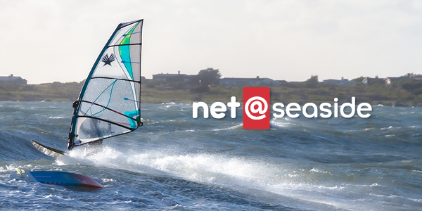 Vågsurfare på surfbräda på ett blåsigt hav och logotype för net at seaside